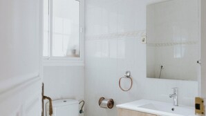 Un baño con inodoro, lavamanos y espejo.