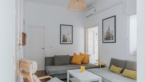 Una sala moderna con un sofá, una mesita, una silla y dos cuadros en la pared.