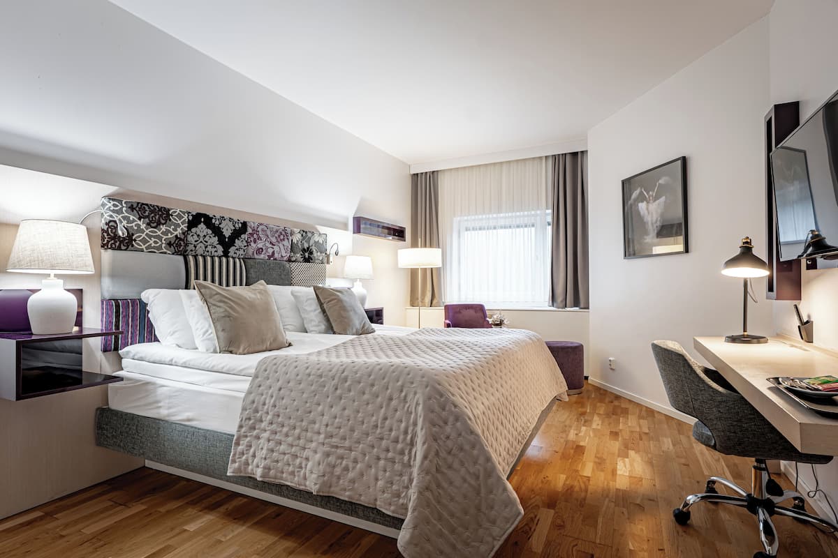 Ein modernes Hotelzimmer mit Bett, Nachttischen, Schreibtisch und Stuhl.