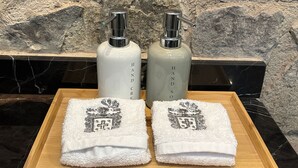 Dos botellas de jabón para manos sobre una bandeja con dos toallas que presentan un diseño de escudo.