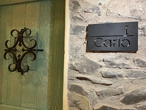 A green door with a decorative metal handle and a stone wall with a sign that reads "I Carlo". - Castello di Carlo - Suite Carlo I (Tetlatlahuca)