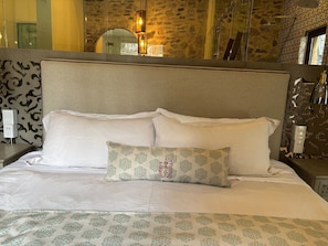 A neatly made bed with a patterned pillow and a headboard against a stone wall. - Castello di Carlo - Suite Carlo I (Tetlatlahuca)