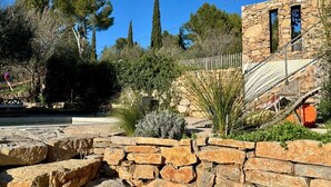 A stone building with a rustic design, surrounded by a stone wall and various plants. - Modern villa with pool in the heart of Provence, 30 minutes from the beaches (Carnoules)