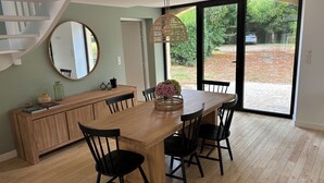 A dining area with a wooden table, black chairs, a mirror, and a large window with a view of a garden and a parked car. - Superb barn in the Dordogne, in the heart of Trémolat (Trémolat)