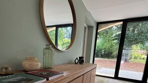 A wooden console with a round mirror, books, and decorative items. - Superb barn in the Dordogne, in the heart of Trémolat (Trémolat)