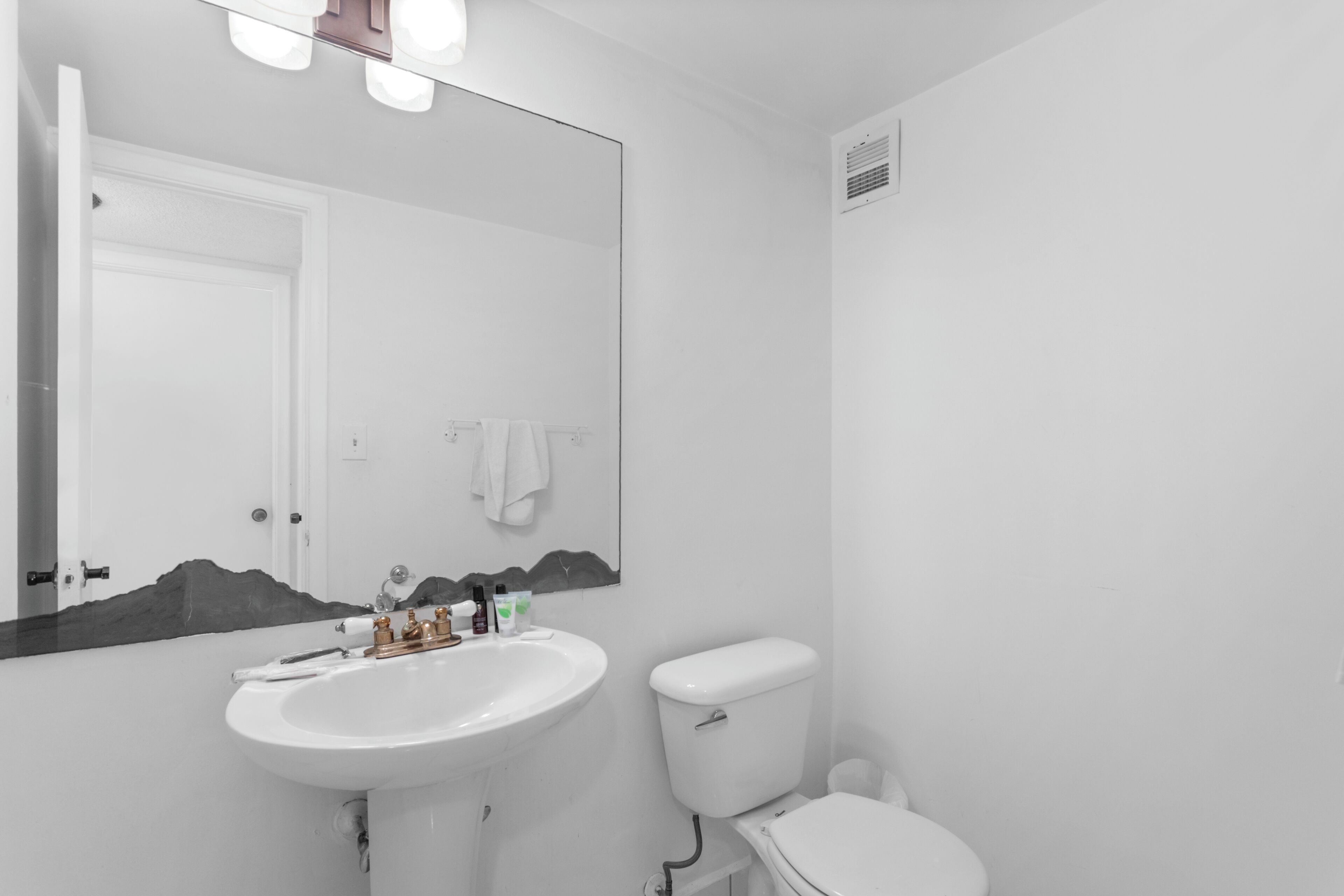 Un baño con lavamanos blanco, inodoro y un espejo grande.