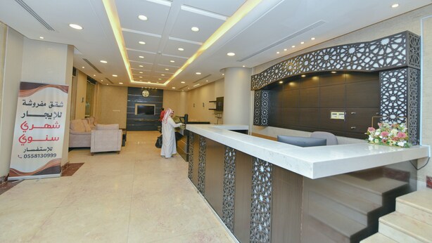 A hotel reception area with a modern design, featuring a reception desk, seating area, and a decorative wall. - Reef Al Kharj Hotel Apartments (Al Kharj)
