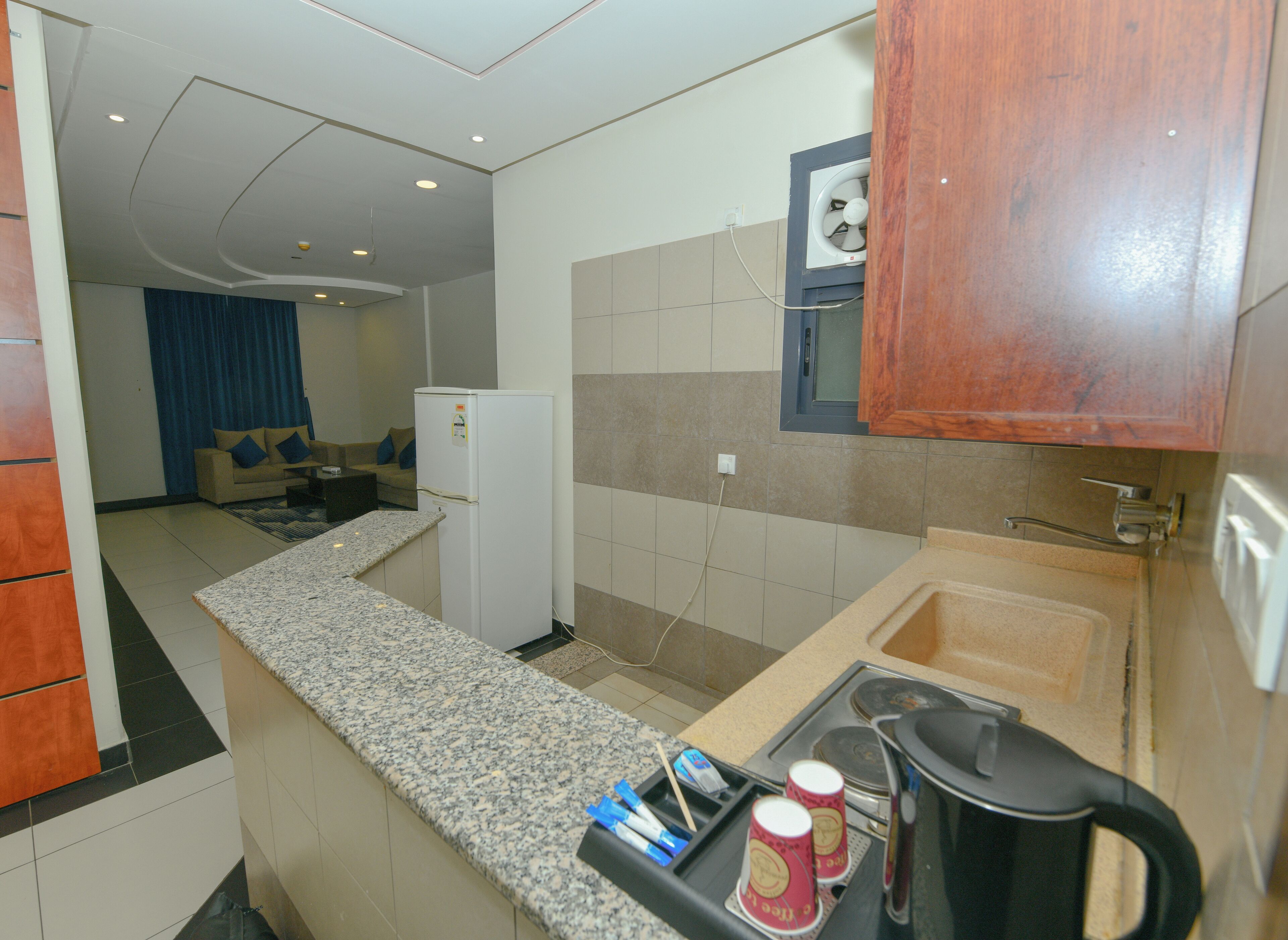 A compact kitchen with a refrigerator, a coffee maker, and a sink.