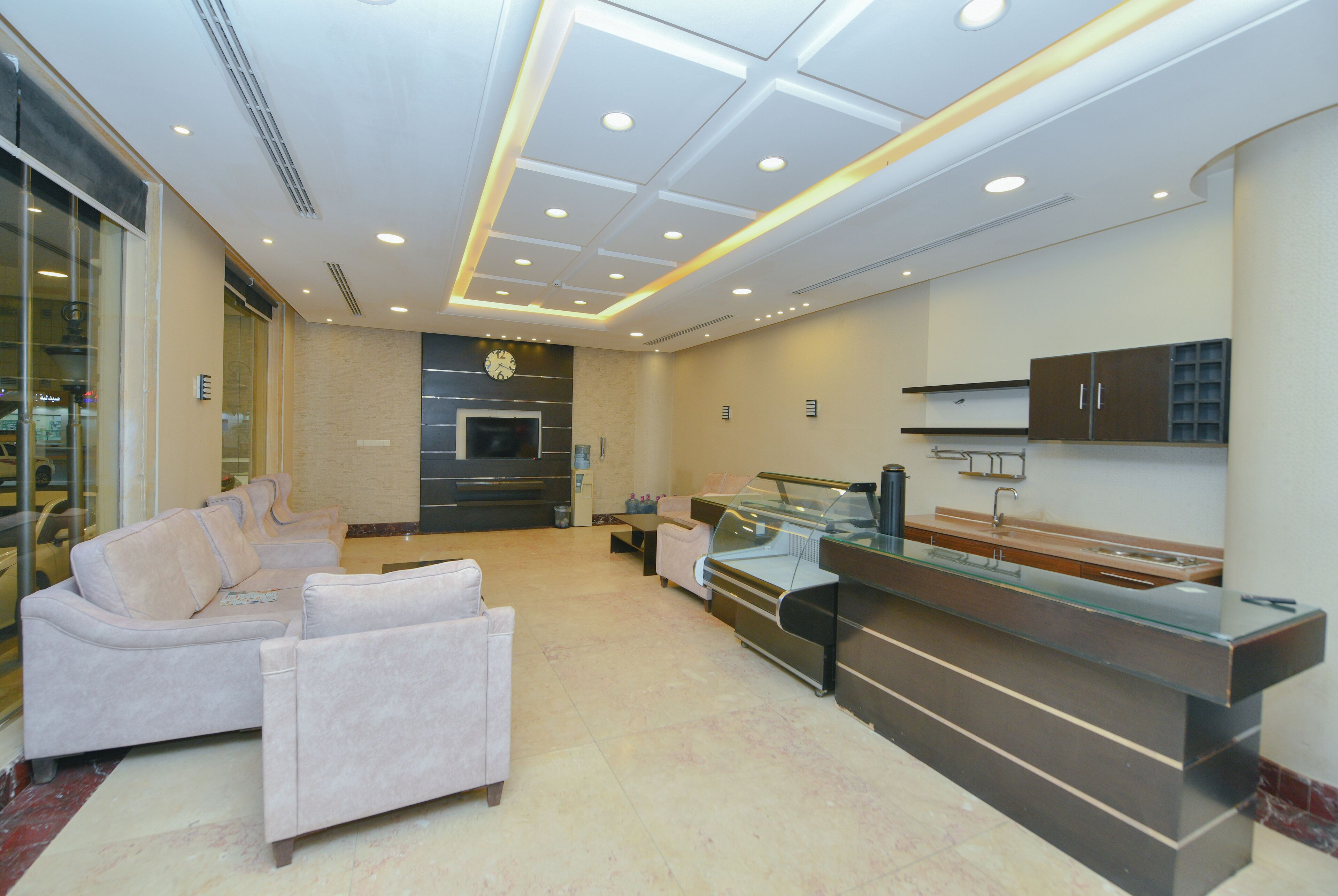 A modern lobby with a seating area, a reception desk, and a kitchen area.