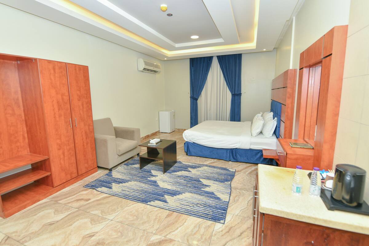 A hotel room with a bed, a sofa, a coffee table, and a wardrobe.