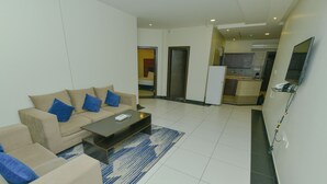 A modern living room with a beige sofa, blue cushions, a coffee table, and a patterned rug. - Reef Al Kharj Hotel Apartments (Al Kharj)