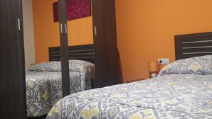 A bedroom with two beds, a wardrobe, and a mirror.