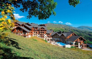A chalet-style hotel with multiple balconies and a swimming pool.