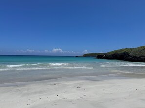 A beach with clear turquoise water, sandy shore, and a rocky outcrop in the background. - Authentic 3 bedroom Vieques house, quiet neighborhood, 10 minute walk to ferry. (Vieques)