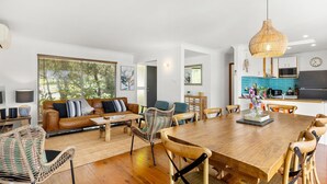 A modern living room with a sofa, chairs, a dining table, and a kitchen area with a microwave and stove.
