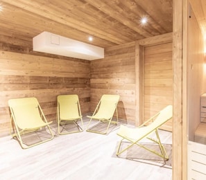 A wooden cabin interior with three yellow lounge chairs arranged in a row.