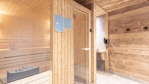 A sauna room with wooden walls and a glass door, a bench, and a small sink. - Wifi, 50m from ski slopes, Ground floor, view mountain/ski slopes, sauna, terrace, parking, tv (Le Grand-Bornand)