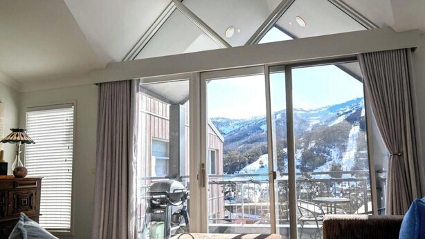 Une pièce spacieuse avec de grandes fenêtres donnant sur des montagnes enneigées.