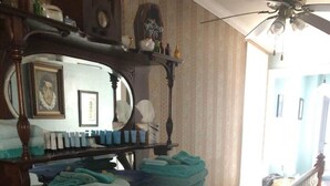 A wooden dresser with folded towels, a mirror, and a shelf with various items. - Poe Themed Home Close to Beaches and DE Turf (Milford)