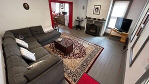 A living room with a sofa, a coffee table, a fireplace, and a television. - Poe Themed Home Close to Beaches and DE Turf (Milford)
