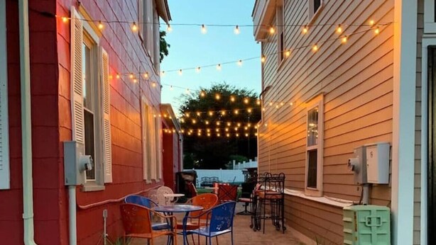 A patio area with outdoor seating, string lights, and potted plants. - Poe Themed Home Close to Beaches and DE Turf (Milford)