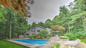 A residential property with a swimming pool, a deck, and a house surrounded by trees.
