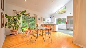 Une cuisine moderne avec une table à manger en verre, des chaises en bois et une grande plante en pot.