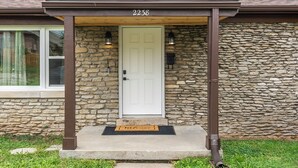 A stone house with a white door, number 2238, and a porch with two lanterns. - Charming Kentucky Stone House (Lexington)