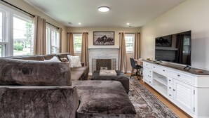 A spacious living room with a fireplace, a large TV, and a comfortable seating area. - Charming Kentucky Stone House (Lexington)