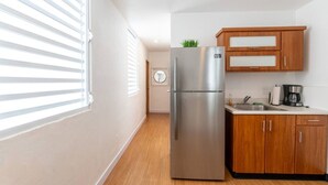 A kitchen with a stainless steel refrigerator, wooden cabinets, a coffee maker, and a window with blinds. - Modern 2-BR Apt. in historic Old San Juan (San Juan)