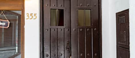 Una porta de fusta fosca amb el número 355, una petita finestra i un timbre.