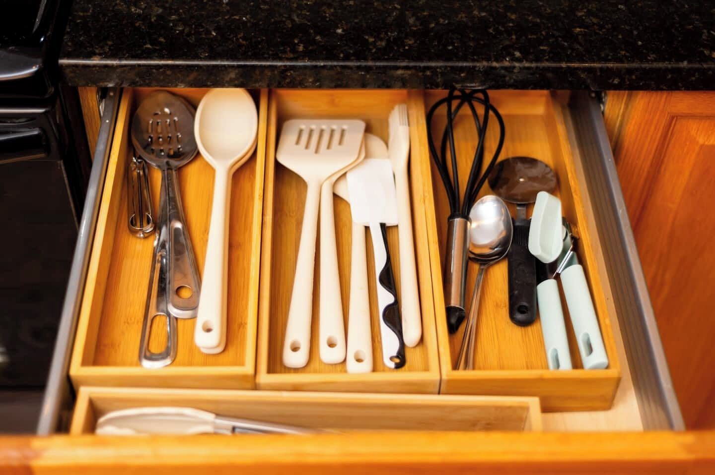 Un cajón de cocina con varios utensilios, incluyendo cucharas, espátulas y batidores.