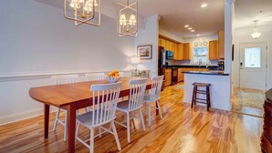 A modern kitchen with wooden cabinets, a central island, and a dining area with a wooden table and white chairs. - Lakeside Landing Spacious Comfort  Near Downtown (North Charleston)