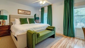 A bedroom with a bed, a green bench, a ceiling fan, and a window with green curtains. - Lakeside Landing Spacious Comfort  Near Downtown (North Charleston)