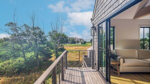 A balcony with a wooden deck, a sofa, and a glass door leading to a room.