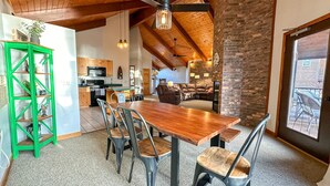 Amplia sala de estar con una mesa de comedor de madera, sillas y un estante verde.