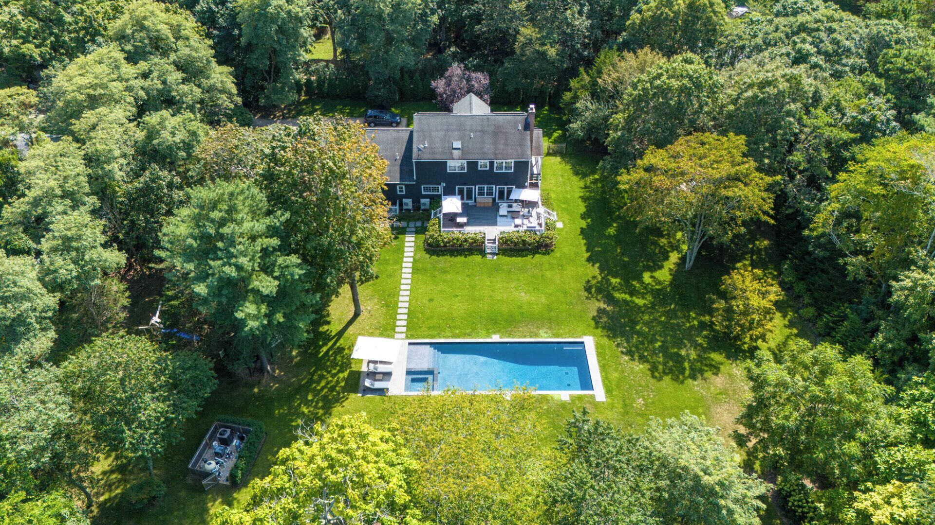 Vista aérea de una casa con piscina, rodeada de árboles densos.