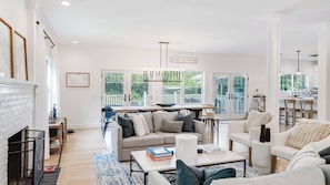 A spacious living room with a fireplace, a dining area, and a kitchen visible through an open door.