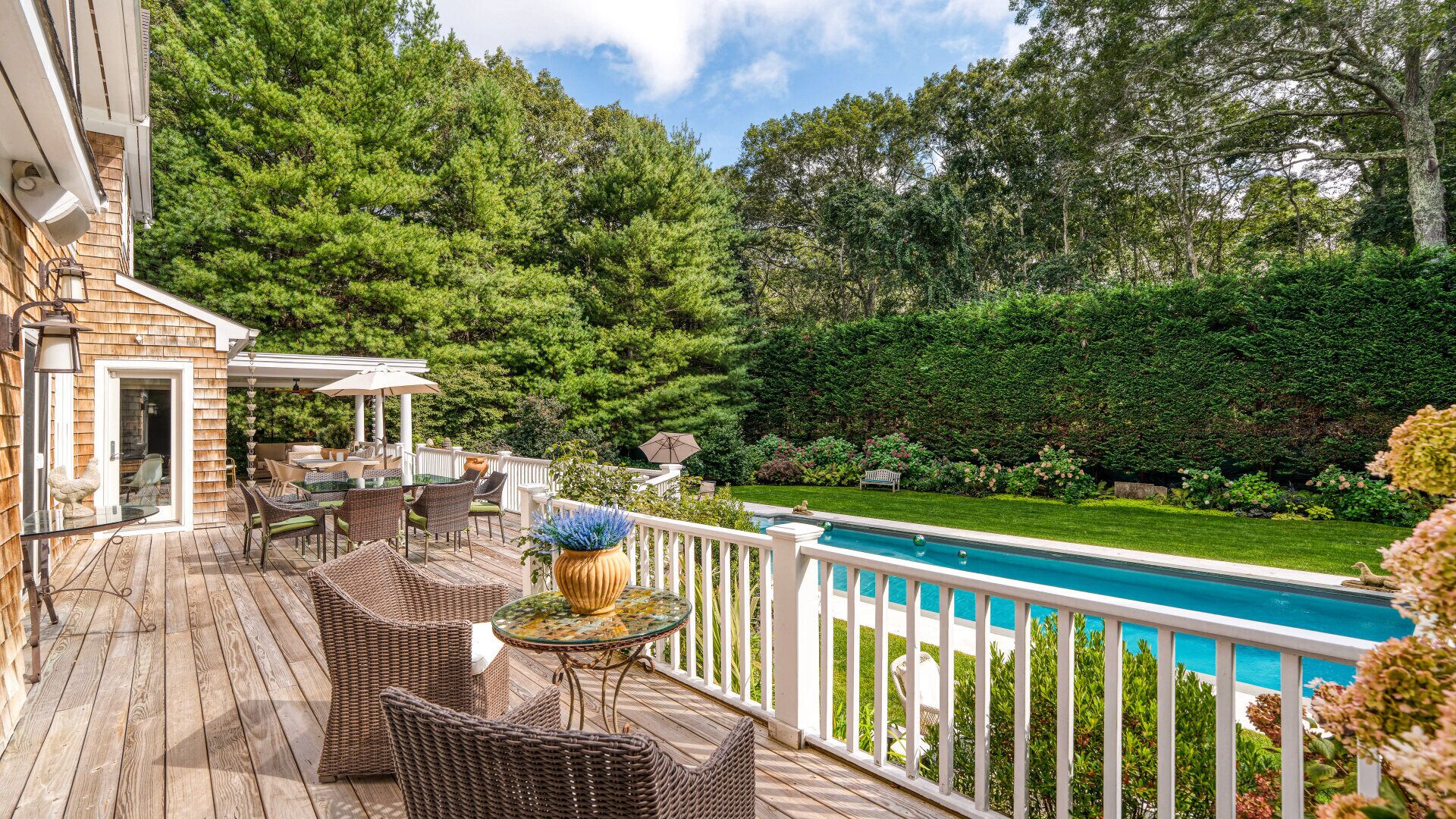A wooden deck with wicker furniture and a pool.