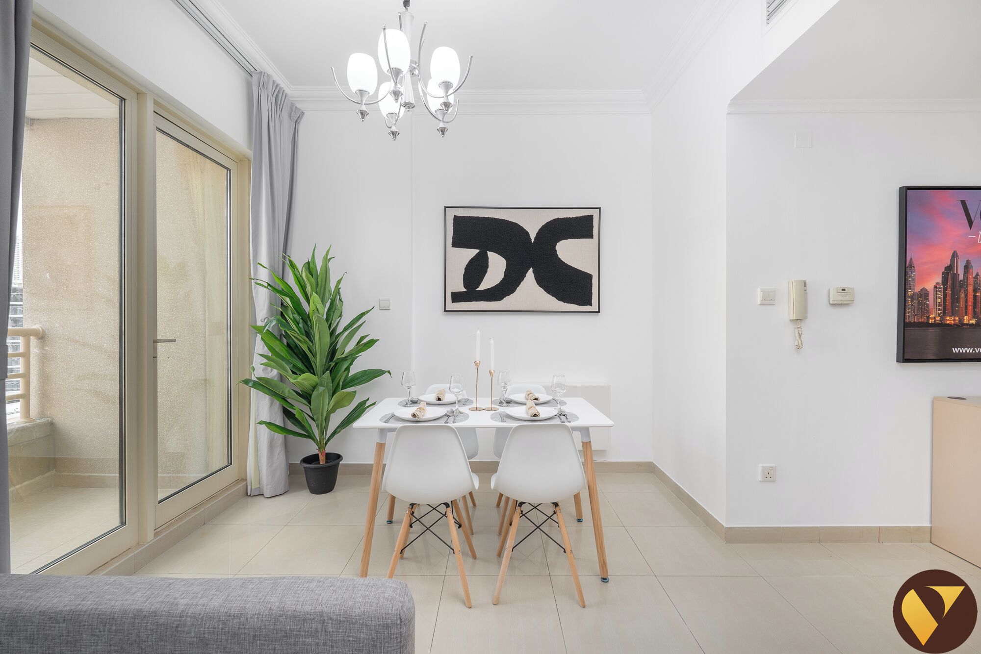 A modern dining area with a table set for four, a potted plant, and a cityscape painting on the wall.