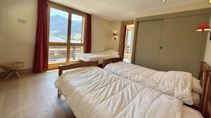 A bedroom with two beds, a window with a view, and a wooden floor. - 2nd floor, balcony, tv, ski locker, 55m², Praz sur Arly (Praz-sur-Arly)