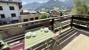 A balcony with a table and chairs, overlooking a mountainous landscape. - 2nd floor, balcony, tv, ski locker, 55m², Praz sur Arly (Praz-sur-Arly)