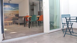 A modern living room with a glass door leading to a dining area.