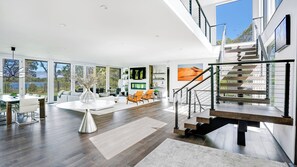 A spacious living area with a large window, a staircase, and a dining area.