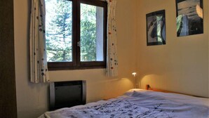 A bedroom with a bed, a window with curtains, a wall-mounted TV, and two framed pictures. - 50m from ski slopes, floor -1, terrace, tv, ski locker, 45m², Risoul (Risoul)