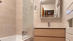 A modern bathroom with a bathtub, a wooden vanity, and a mirror above the sink. - 50m from ski slopes, floor -1, terrace, tv, ski locker, 45m², Risoul (Risoul)
