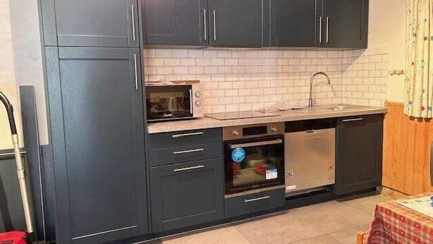 A compact kitchen with dark cabinets, a microwave, an oven, and a sink. - 50m from ski slopes, floor -1, terrace, tv, ski locker, 45m², Risoul (Risoul)