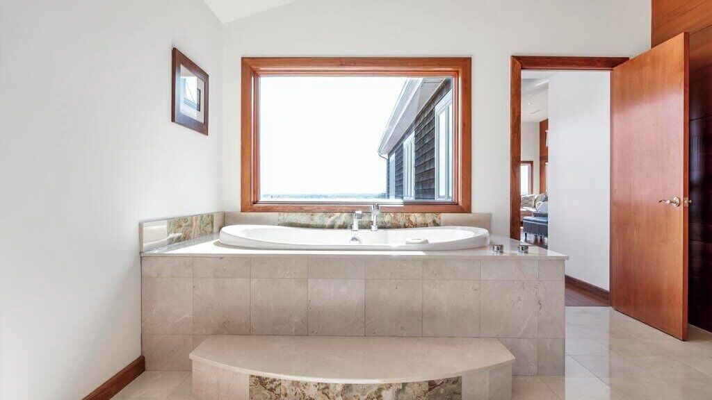 Une salle de bain avec une grande fenêtre, un lavabo et un miroir.