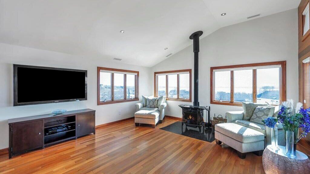 A spacious living room with a large flat-screen TV, a fireplace, and a city view through large windows.