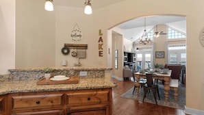 A kitchen with granite countertops, wooden cabinets, and a dining area with a table and chairs. - Penthouse Table Rock Lake View  Near SDC (Branson)